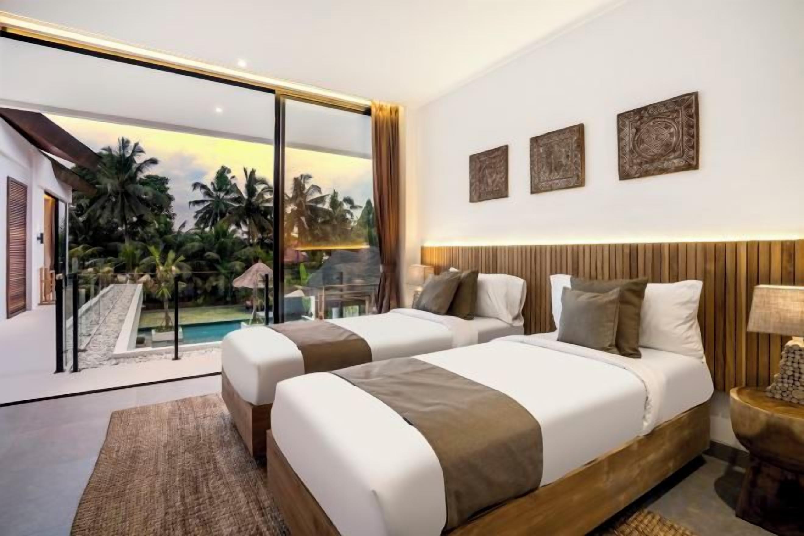 A hotel room with two beds, a large window, and a view of a pool and palm trees.