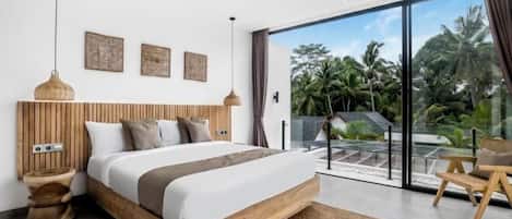 A modern bedroom with a large bed, wooden headboard, and a view of tropical vegetation through large glass doors.