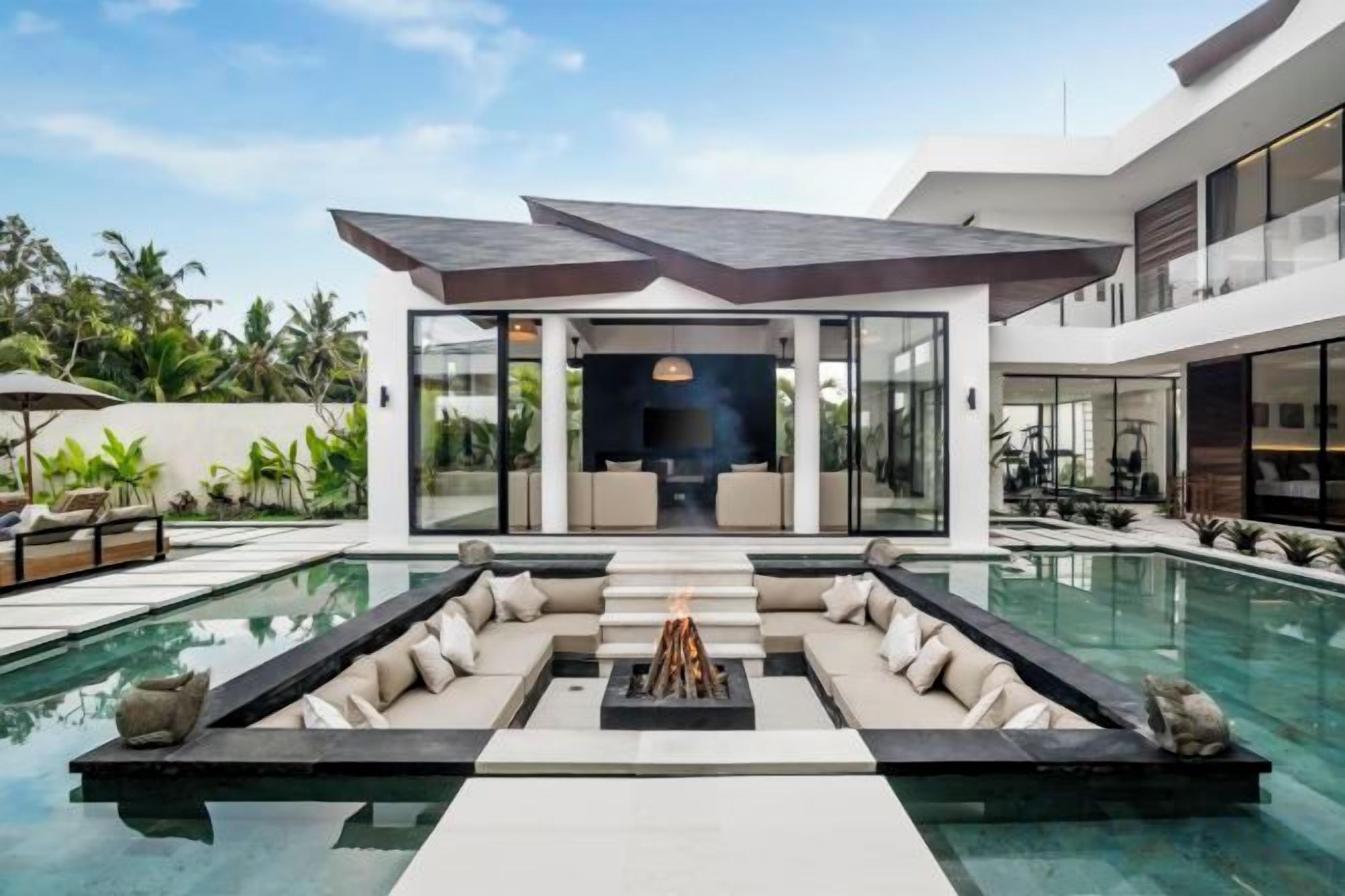 A modern house with a swimming pool, outdoor seating, and a fire pit.
