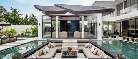A modern house with a swimming pool, outdoor seating, and a fire pit.