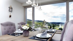 A dining table set with plates, glasses, and a vase of flowers, overlooking a scenic landscape. - Apartment 'Chillout' with Spa Area and Mountain View (Ibach)