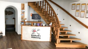 A wooden staircase with a logo, a reception desk, and framed certificates on the wall. - Apartment 'Chillout' with Spa Area and Mountain View (Ibach)
