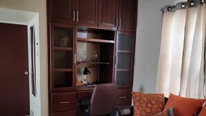 A living room with a brown sofa, a small table, and a wooden cabinet with glass doors. - House 2121. (Juárez)