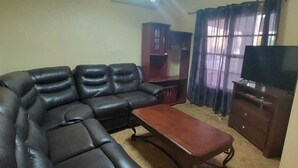 A living room with a sectional sofa, a coffee table, a TV stand, and a ceiling fan. - House 2121. (Juárez)
