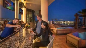 A bar area with a marble countertop, a large column, and a view of a pool and buildings at dusk. - Beautiful Hyde Resort Luxe 2BR Private Beachfront (Hollywood)