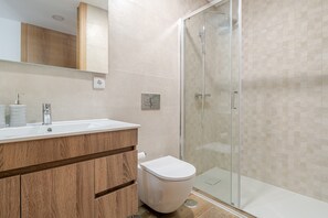 Un bagno moderno con un mobile bagno in legno, un water e una cabina doccia in vetro.