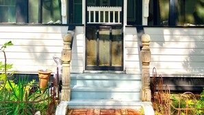 A white building with a porch featuring a black gate and a small porch area with a white railing.