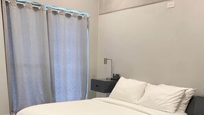 Un dormitorio moderno con una cama grande, una mesita de noche y una lámpara de pared.
