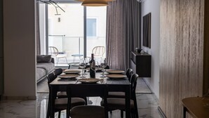 A dining area with a table set for four, a modern pendant light, and a view of the balcony. - Coastal Elegance, Steps from the Sea (Sliema)