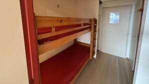 A room with a bunk bed, a door, and a small window. - 300m from ski lifts, 1st floor, balcony, tv, ski locker, 28m², Alpe d'Huez (L'Alpe d'Huez)