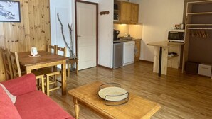 A compact living space with a dining area, a kitchenette, and a red sofa.