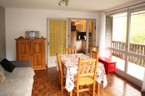A dining area with a table set for four, a wooden cabinet, and a kitchen visible through an open door. - 50m from ski slopes, 1st floor, balcony, 40m², Les Orres (Les Orres)