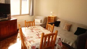 Ein gemütliches Wohnzimmer mit Holztisch, einer Couch und einem Fernseher.