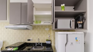 A kitchen with a microwave, refrigerator, sink, and cabinets.