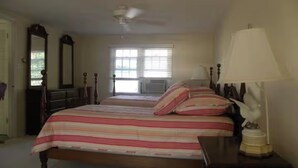 A bedroom with a large bed, a dresser, a mirror, and a ceiling fan.