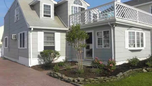 A two-story house with a covered porch and a small garden.