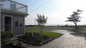 A house with a small garden, a paved driveway, and a view of the sea.