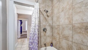 A bathroom with a bathtub, shower, and tiled walls. - Vibrant Memphis Retreat | Steps from Local Spots (Memphis)