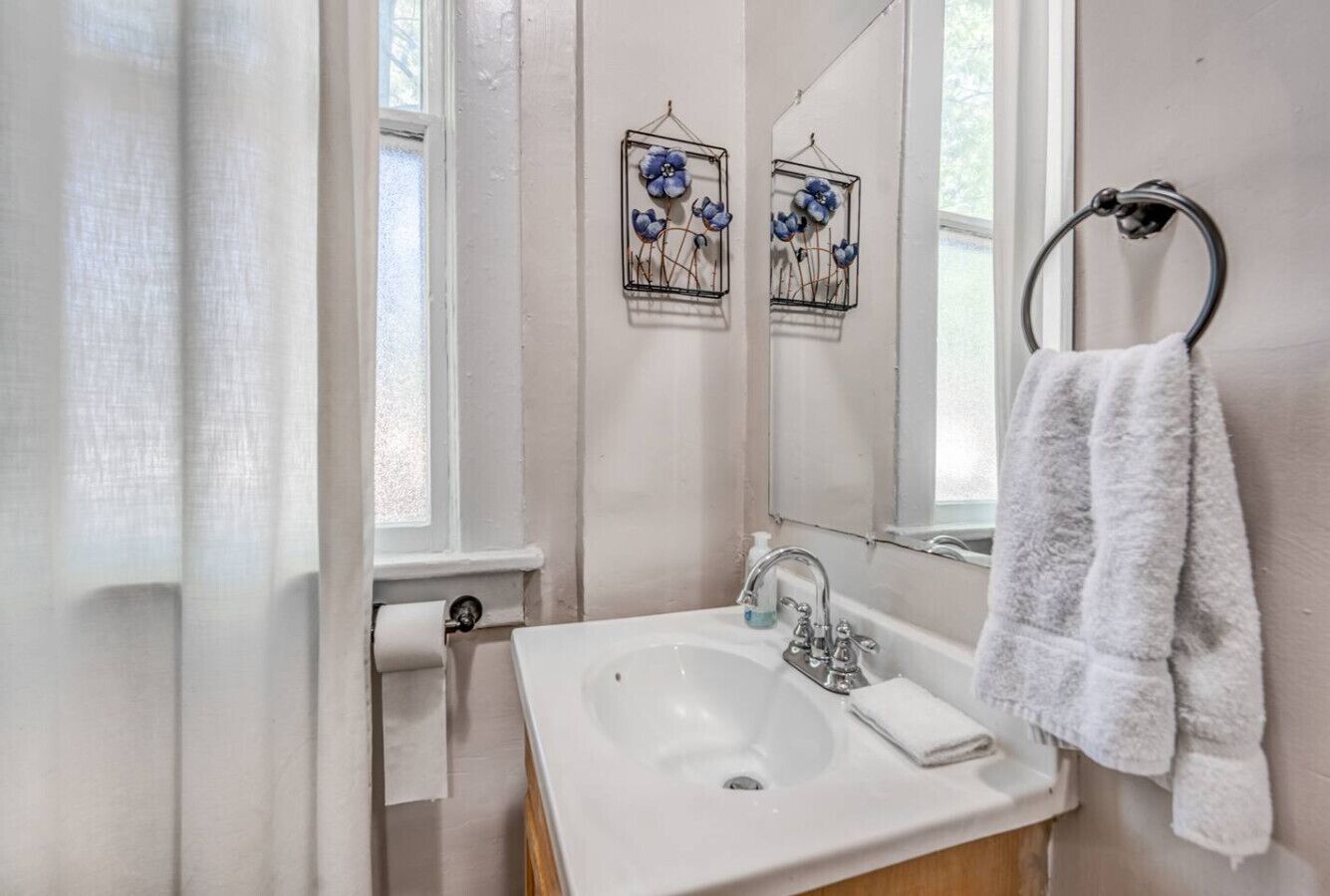 A bathroom with a white sink, a towel rack with a white towel, and two wall-mounted flower decorations.