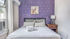 A neatly made bed with a white duvet, two pillows, and a rolled towel. There is a framed artwork on the wall above the bed. - Vibrant Memphis Retreat | Steps from Local Spots (Memphis)
