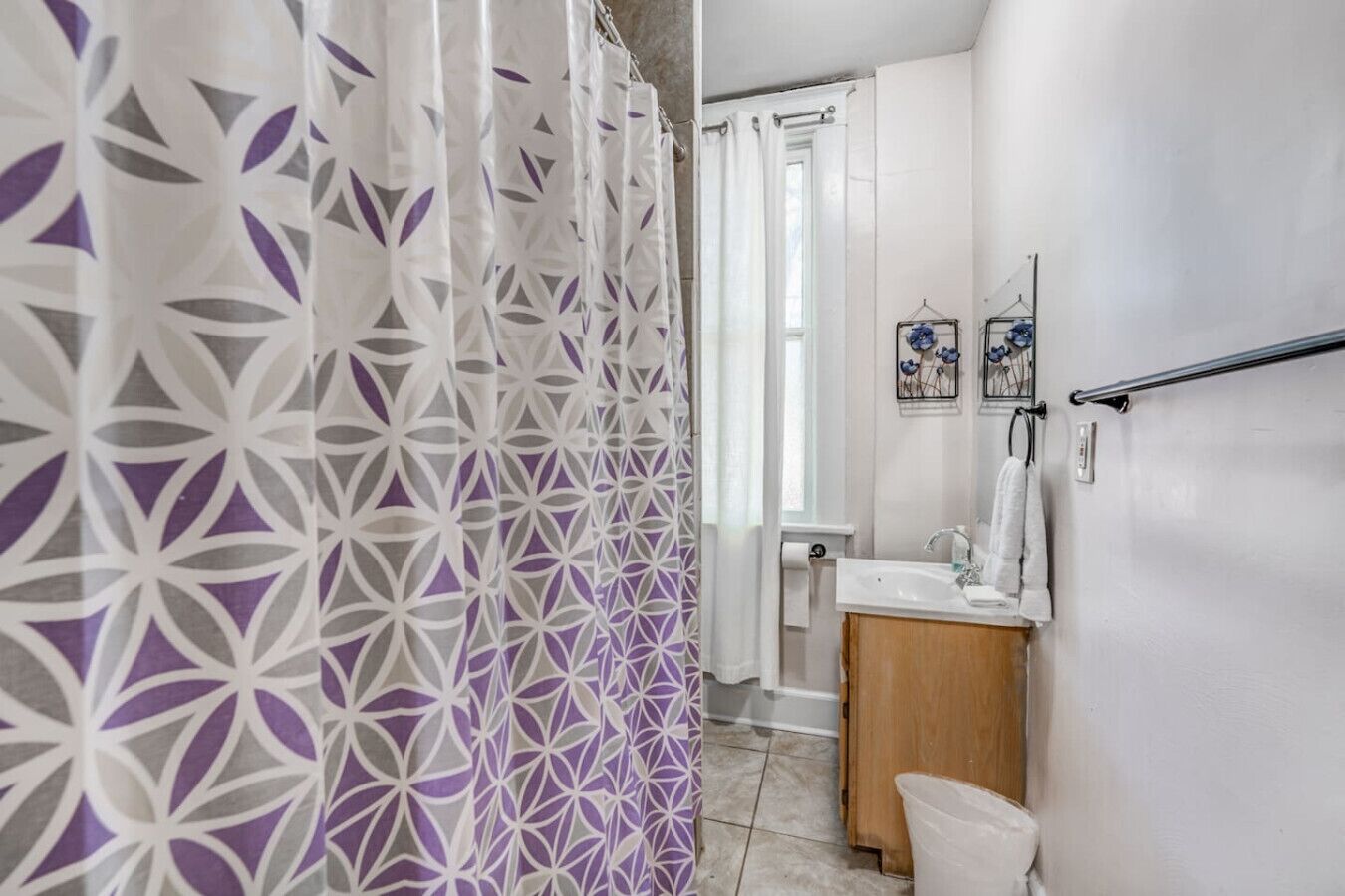 A bathroom with a shower curtain, a sink, and a mirror.