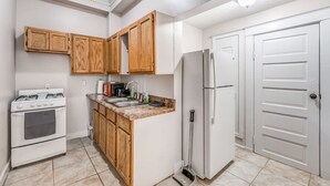 A compact kitchen with wooden cabinets, a white refrigerator, a stove, and a sink. - Vibrant Memphis Retreat | Steps from Local Spots (Memphis)