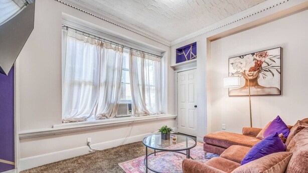 A living room with a sofa, a glass coffee table, and a patterned rug. - Vibrant Memphis Retreat | Steps from Local Spots (Memphis)