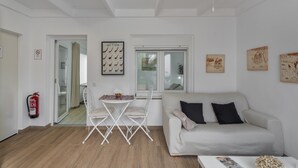 Una sala de estar moderna con un sofá blanco, una mesa de comedor con sillas, un ventilador de techo y obras de arte en las paredes.