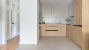 Una cocina moderna con armarios de madera clara, encimera negra y salpicadero de azulejos.