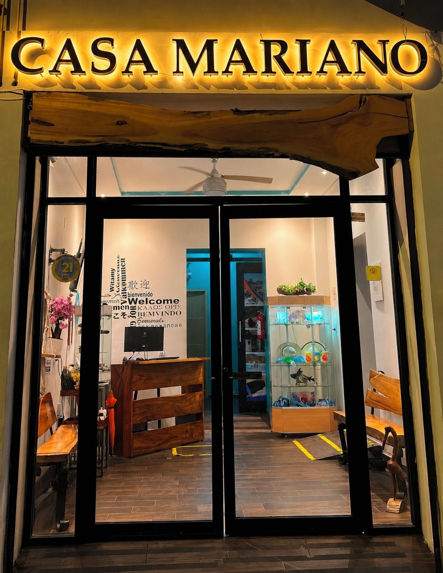 L’entrée de CASA MARIANO est marquée par une enseigne au-dessus des portes, un comptoir d’accueil et une vitrine en verre contenant divers objets.