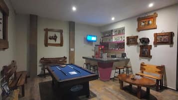 A billiards table, bar area, and seating in a room.