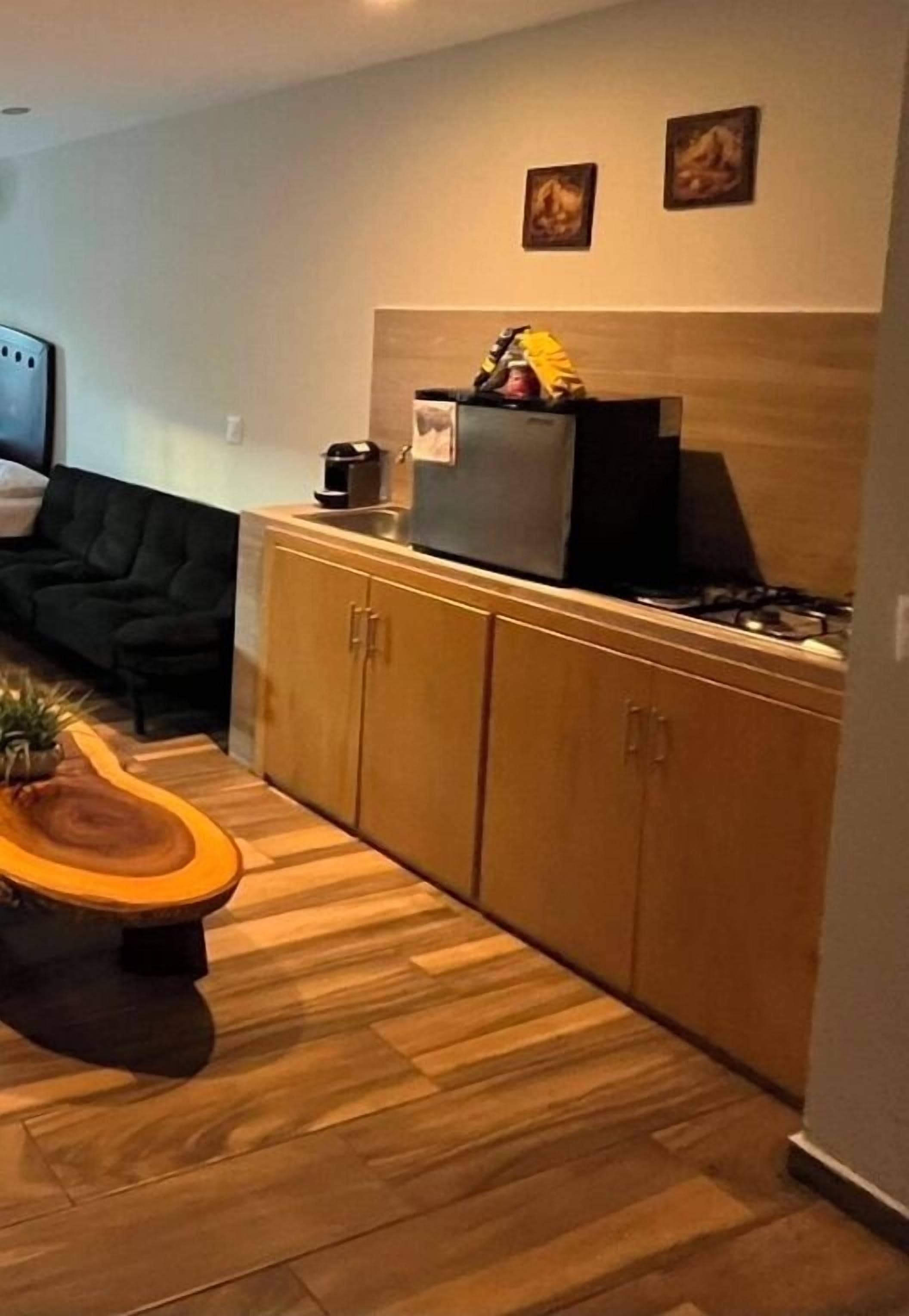 Una cocina compacta con armarios de madera, estufa integrada y un refrigerador pequeño.