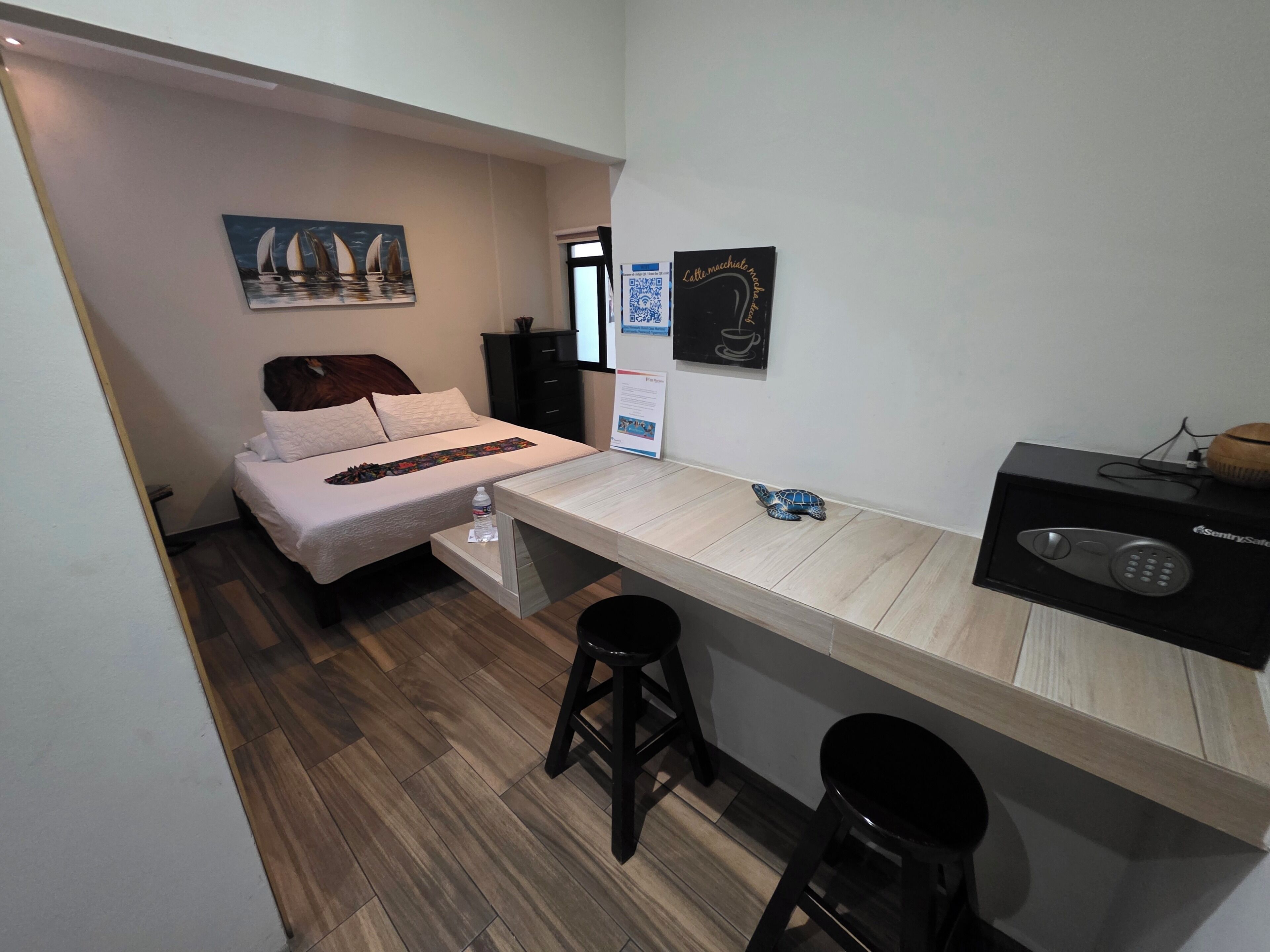 Habitación pequeña con una cama, un escritorio con computadora y un taburete.