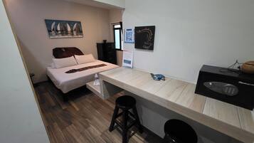 Habitación pequeña con una cama, un escritorio con computadora y un taburete.