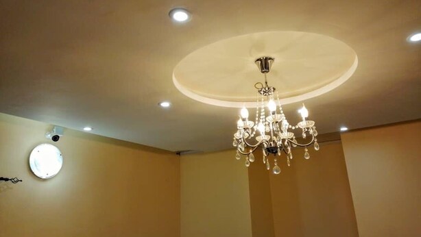 A room with a chandelier, recessed ceiling lights, and a circular light fixture on the wall. - Cozy 1-bedroom apartment in beautiful Lomé with AC and internet. (Lomé)