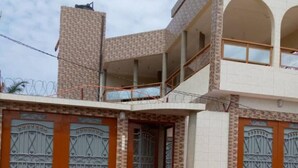 A two-story building with a balcony and a gated entrance. - Cozy 1-bedroom apartment in beautiful Lomé with AC and internet. (Lomé)