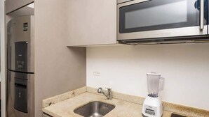 Eine Küche mit einem Edelstahl-Kühlschrank, einer Mikrowelle und einem weißen Mixer auf der Arbeitsfläche.