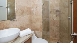 Ein Badezimmer mit einer Duschkabine, einem weißen Waschbecken und einer Toilette.