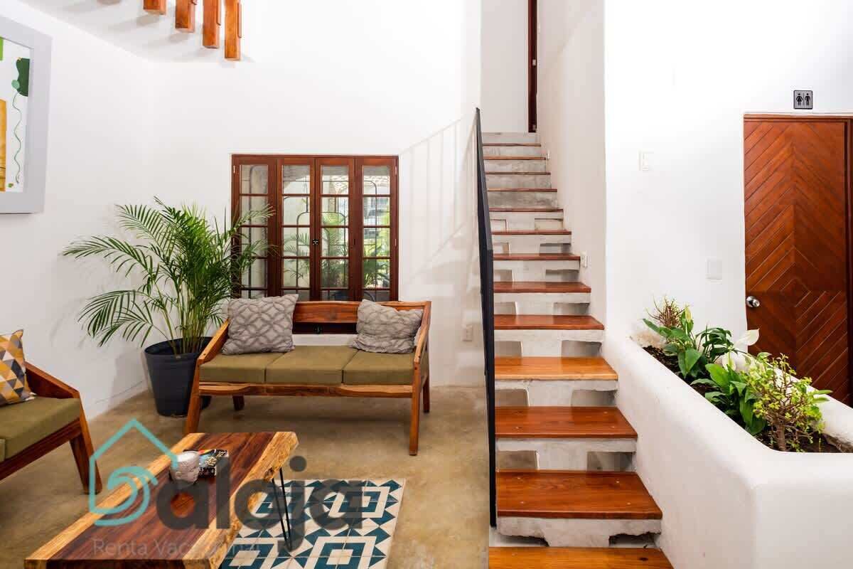 A modern living room with a sofa, a coffee table, and a staircase.