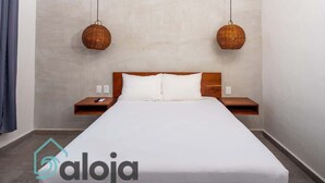 A hotel room with a large bed, two bedside tables, and two wicker wall hangings.