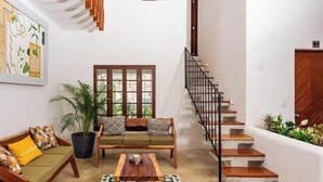 A living room with a sofa set, a coffee table, a potted plant, and a staircase.
