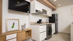 A modern kitchen with a flat-screen TV, built-in appliances, and a minimalist design. - Modern Apartment Pool, BBQ, and Prime Location (Cancún)