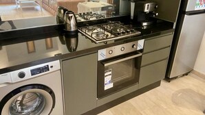 Cocina compacta con estufa a gas, horno, lavadora integrada y refrigerador.