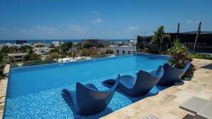 A swimming pool with modern seating and a view of the ocean. - Charming Stay – 5 Minutes from Walmart & 5th Avenue (Playa del Carmen)
