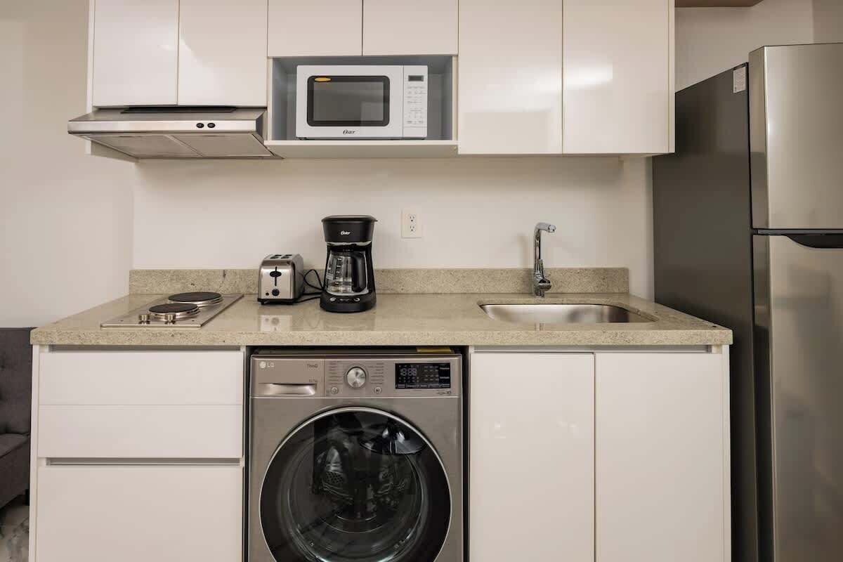 A compact kitchen with a microwave, coffee maker, toaster, sink, dishwasher, and refrigerator.