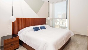 A modern bedroom with a wooden headboard, a white bedspread, and a nightstand with drawers.