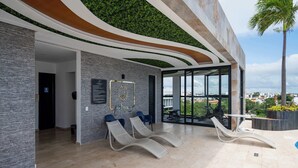 Un'area interna moderna con parete verde, reception e poltrone lounge.