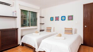 Habitación con dos camas, ventana, aire acondicionado y decoración en la pared.