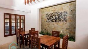 A dining area with a wooden table and chairs, a stone wall with a tree mural, and a window with a view. - Strategically located suite with desk (Cancún)