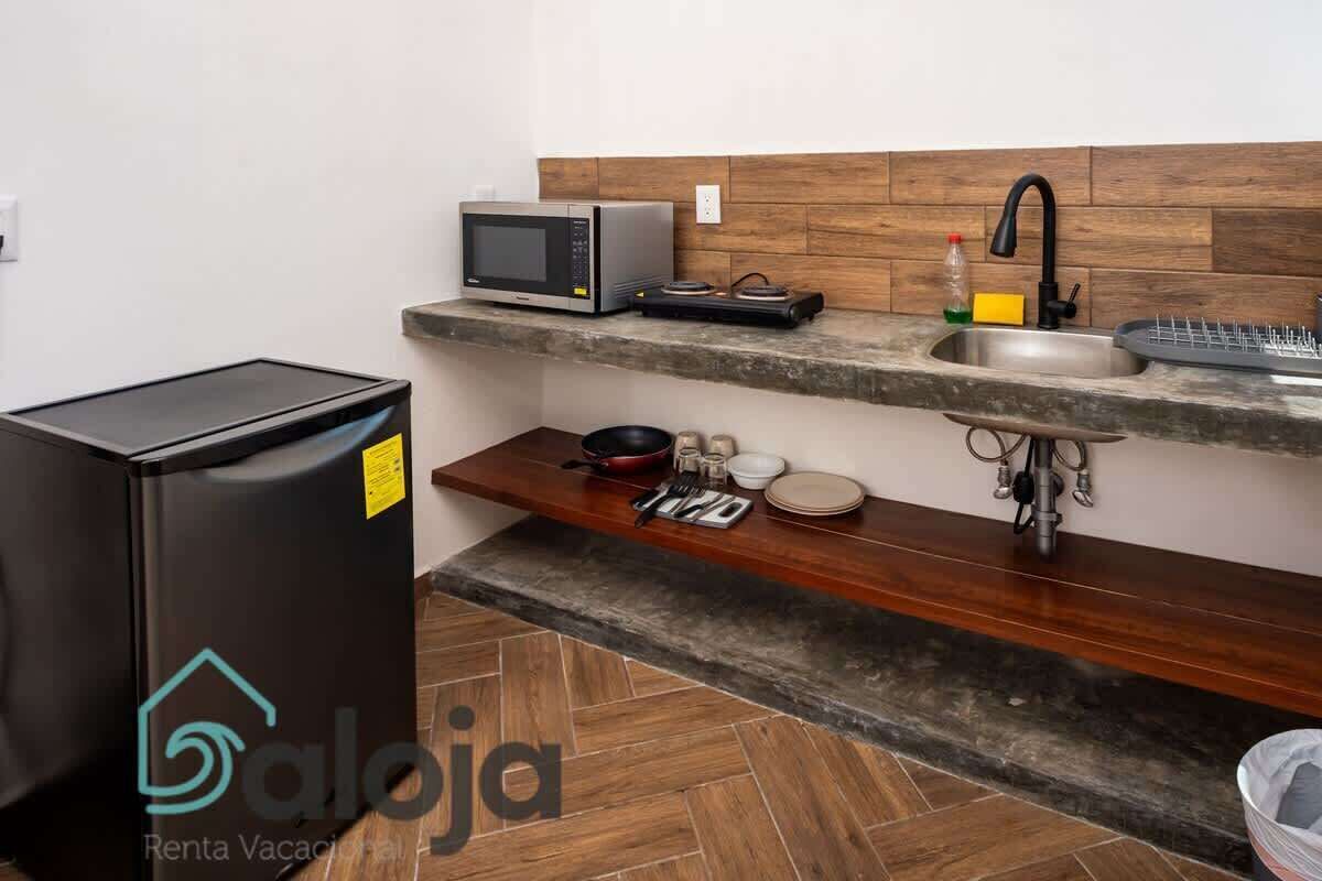 Una cucina compatta con forno a microonde, lavello e piccolo frigorifero.